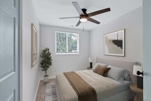 A bedroom with a bed, a ceiling fan, and a small tree.