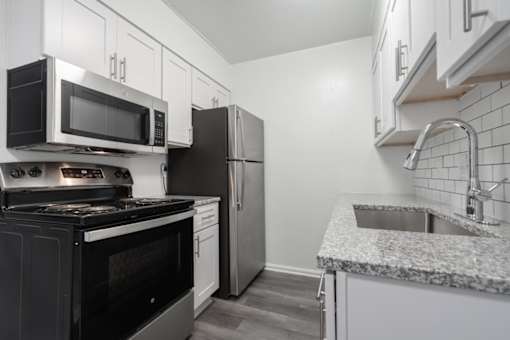 A kitchen with black appliances and white cabinets.