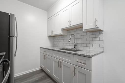A kitchen with white cabinets and a black refrigerator.