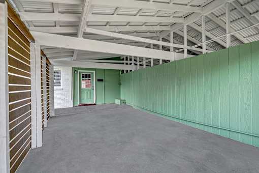 A long hallway with a green wall and a door at the end.