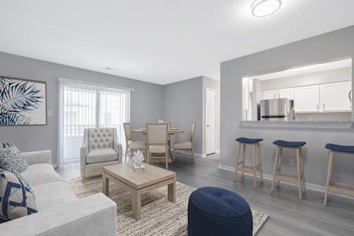 A living room with a grey couch, a coffee table, and a dining area in the background.