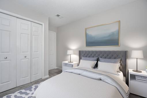 A bedroom with a large bed, two nightstands, and a painting on the wall.