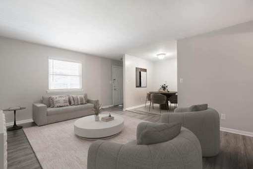 A living room with a grey couch, a white coffee table, and a grey armchair.