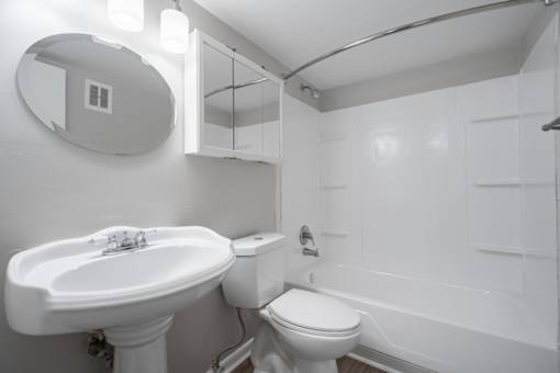 A white bathroom with a sink, toilet and bathtub.