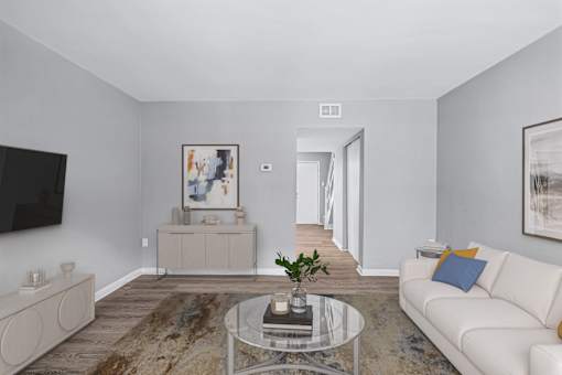 A living room with a white couch and a glass coffee table.