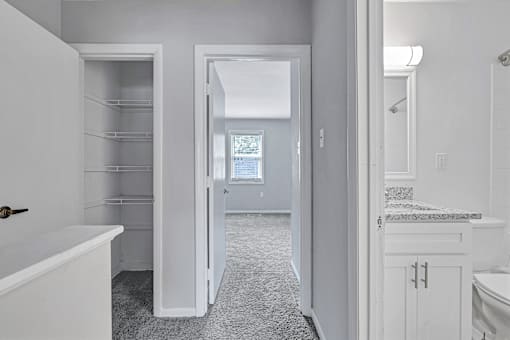 A white bathroom with a tub, sink, and a walk-in closet.