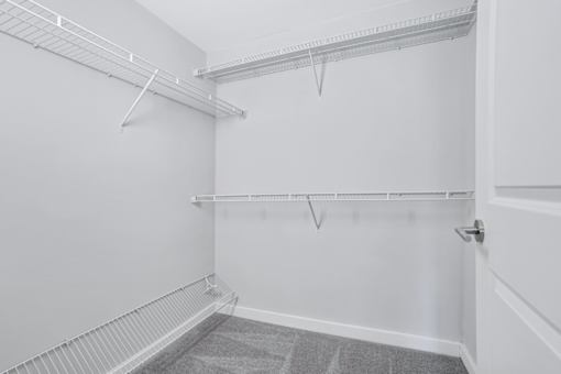 an empty closet with white walls and a white door