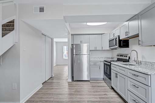 A kitchen with a refrigerator, microwave, and oven.
