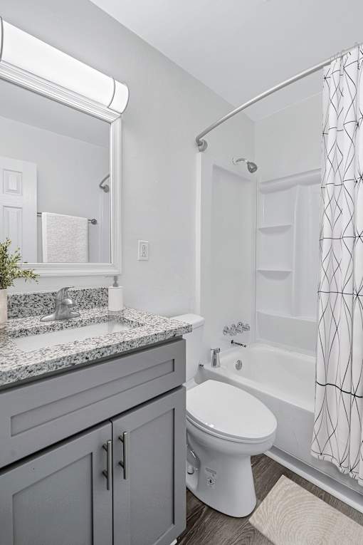 A white toilet sits in a bathroom with a grey counter top.