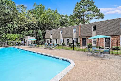 A swimming pool surrounded by chairs and trees.