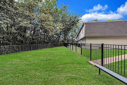 A black metal fence surrounds a green lawn.