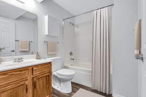 A white bathroom with a toilet, sink, and shower.