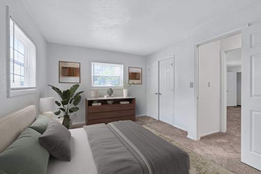 A bedroom with a bed, nightstand, and two windows.