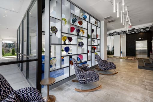 a room with a wall of colorful flowers on the wall and three rocking chairs in front of