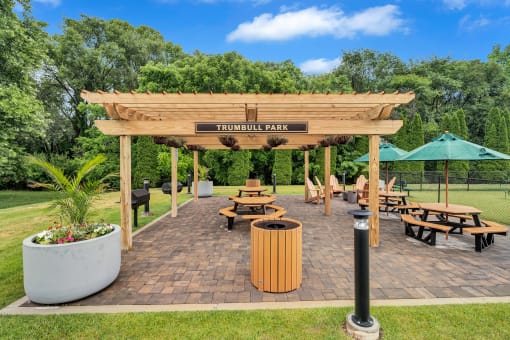 a wooden pergola with benches and tables in a park