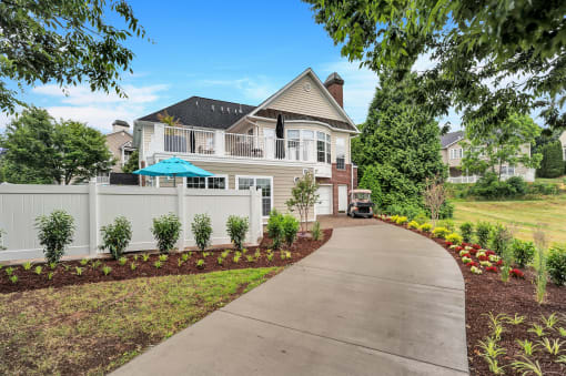 a large white house with a gray roof and a gray sidewalk in front of it
