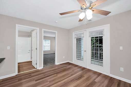 A room with a ceiling fan and wooden floors.