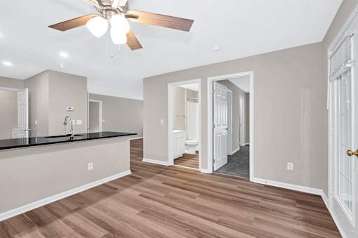 A spacious kitchen with a ceiling fan and wooden flooring.