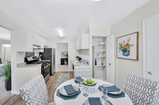 a dining area with a table and chairs and a kitchen in the background