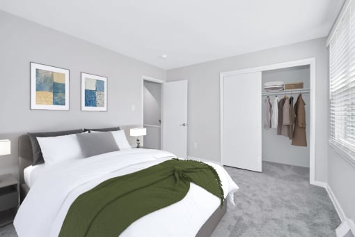 a bedroom with gray walls and a white bed with a green blanket