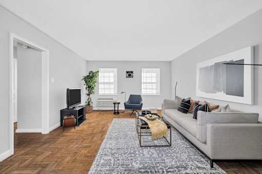 A living room with a grey couch, a coffee table, a television, and a plant.