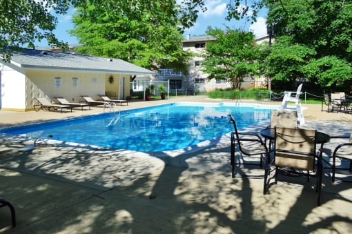 a swimming pool in a backyard with chairs and a table