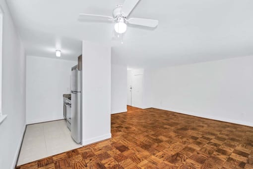 an empty room with a ceiling fan and a stove in the corner