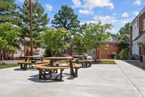 a group of picnic tables on a sidewalk in front of a building