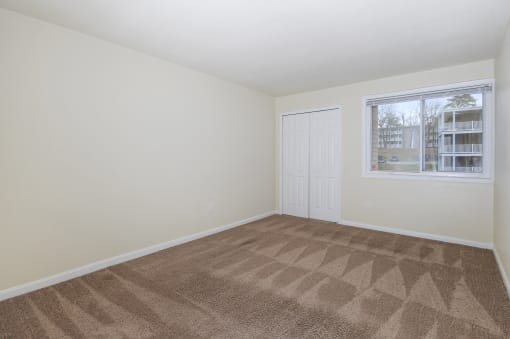 an empty living room with carpet and a window