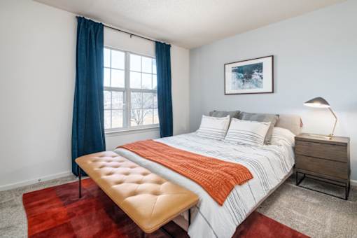 A bedroom with a large bed and a bench in front of it.