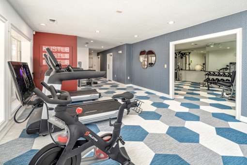 A black exercise bike is in a room with a blue and white checkered floor.
