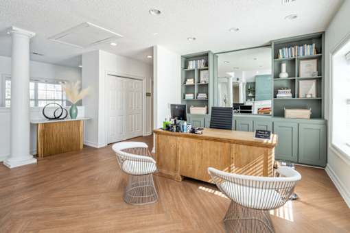 A reception area with a wooden desk and two chairs.