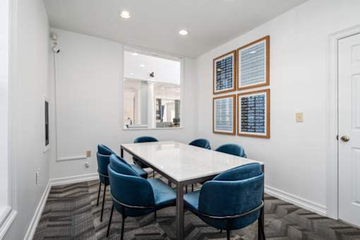 A conference room with a white table and blue chairs.
