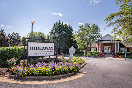 A sign for Hideaway Townhomes is in front of a house.
