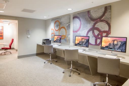 a conference room with four computer desks and a mural on the wall