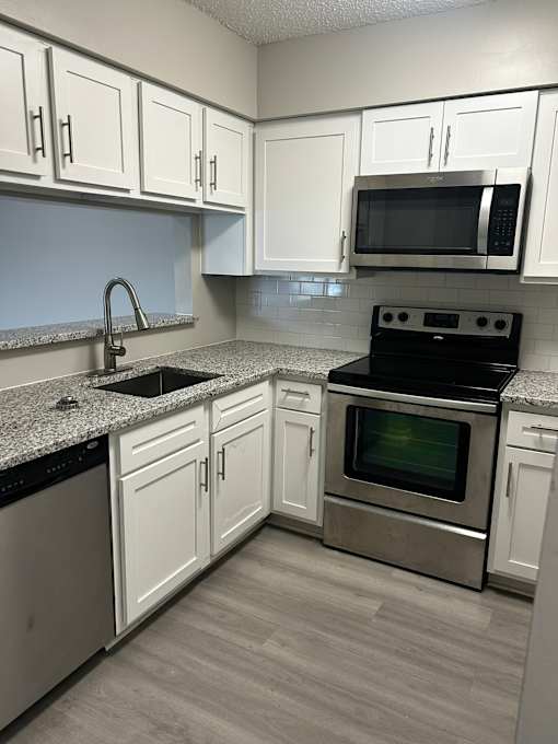 A kitchen with white cabinets and a black stove top oven.
