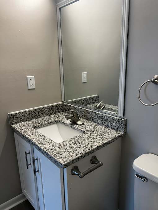 A bathroom with a granite countertop and a white toilet.