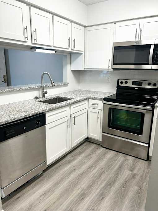 A kitchen with white cabinets and a black oven.