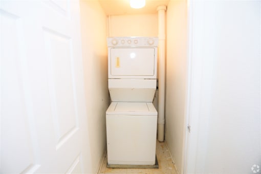A white washing machine in a small white room.