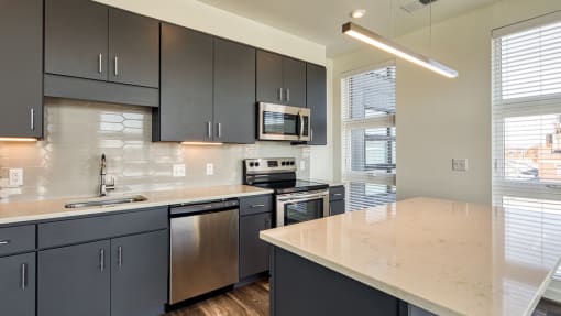 a kitchen with a marble counter top and black cabinets