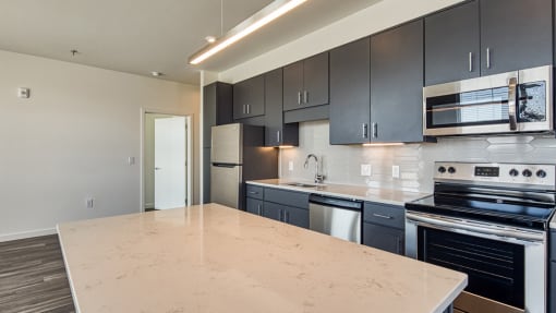 an empty kitchen with black cabinets and a white counter top