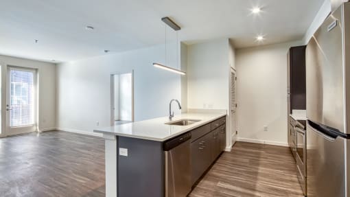an empty kitchen with stainless steel appliances and wood flooring