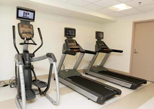 Three treadmills and a stationary bike are lined up in a row.