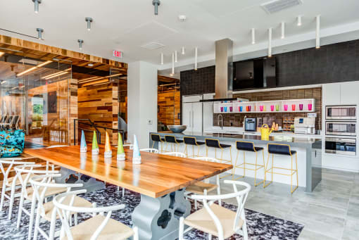 a long wooden table with chairs and a kitchen in the background