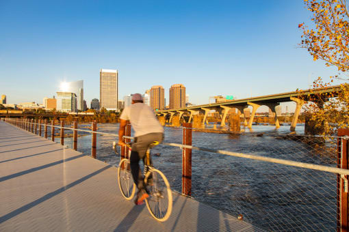a man riding a bike on a bridge with a city in the background
