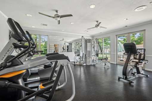 A spacious gym with a variety of exercise equipment and a ceiling fan.