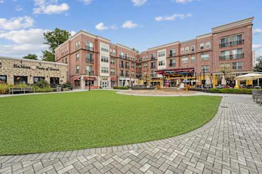 A large grassy area in front of a building with a brick walkway.
