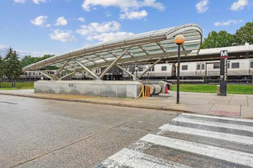 A train station with a train on the tracks and a pedestrian crossing in front.