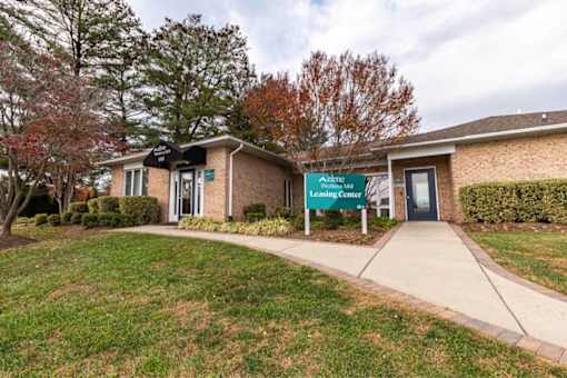 A leasing center is located in a building with a brick exterior and a green lawn in front.