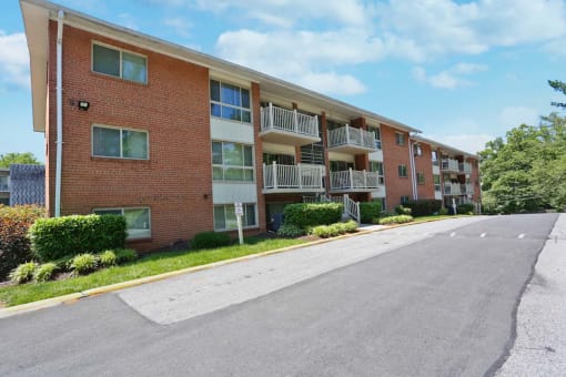 A red brick apartment building with a parking lot in front.